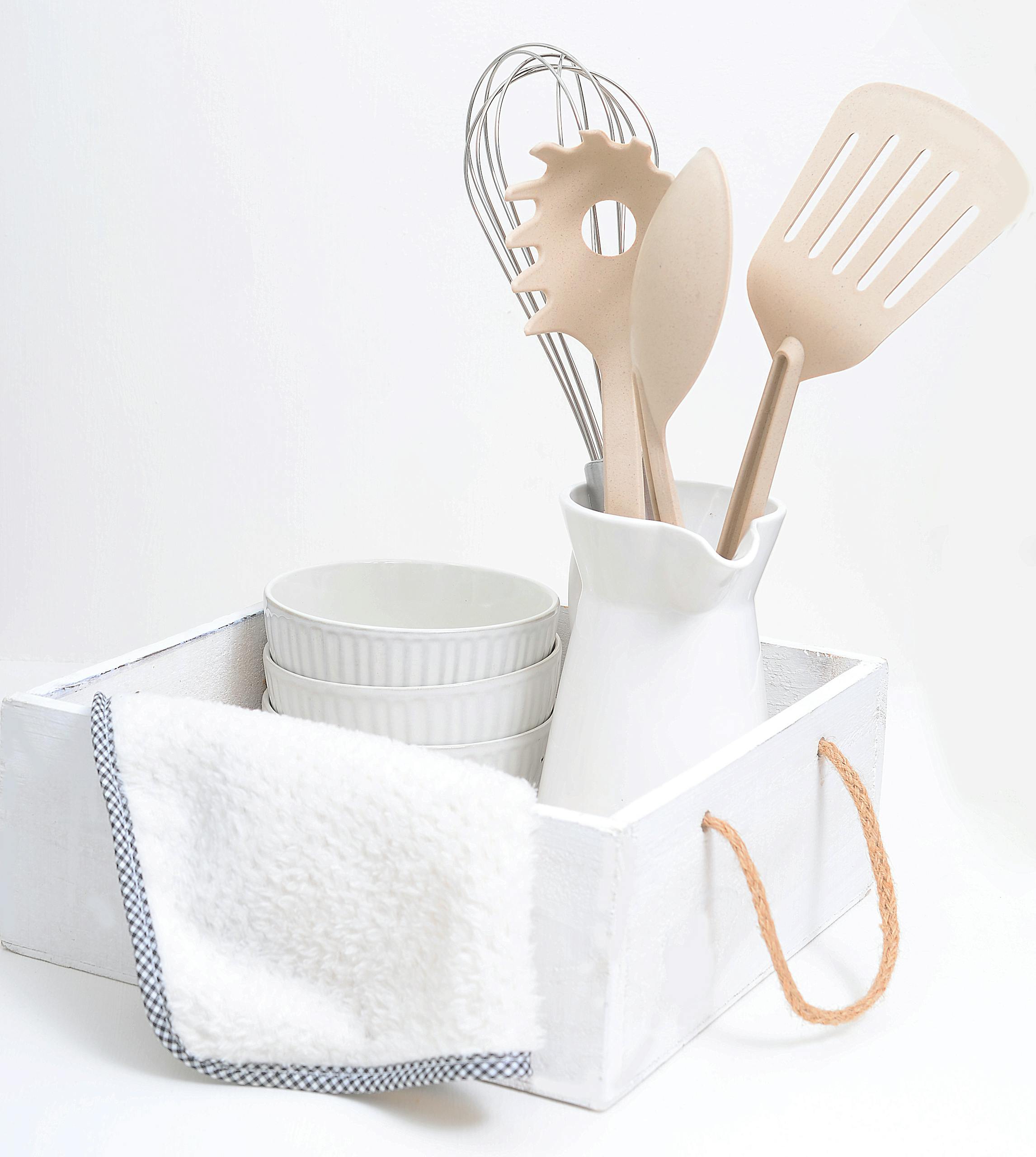 A chic arrangement of white kitchen utensils and decor in a rustic tray for modern elegance.