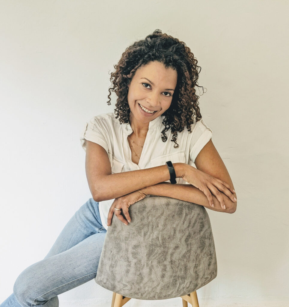 Vanessa Adelle sitting on a chair smiling playfully