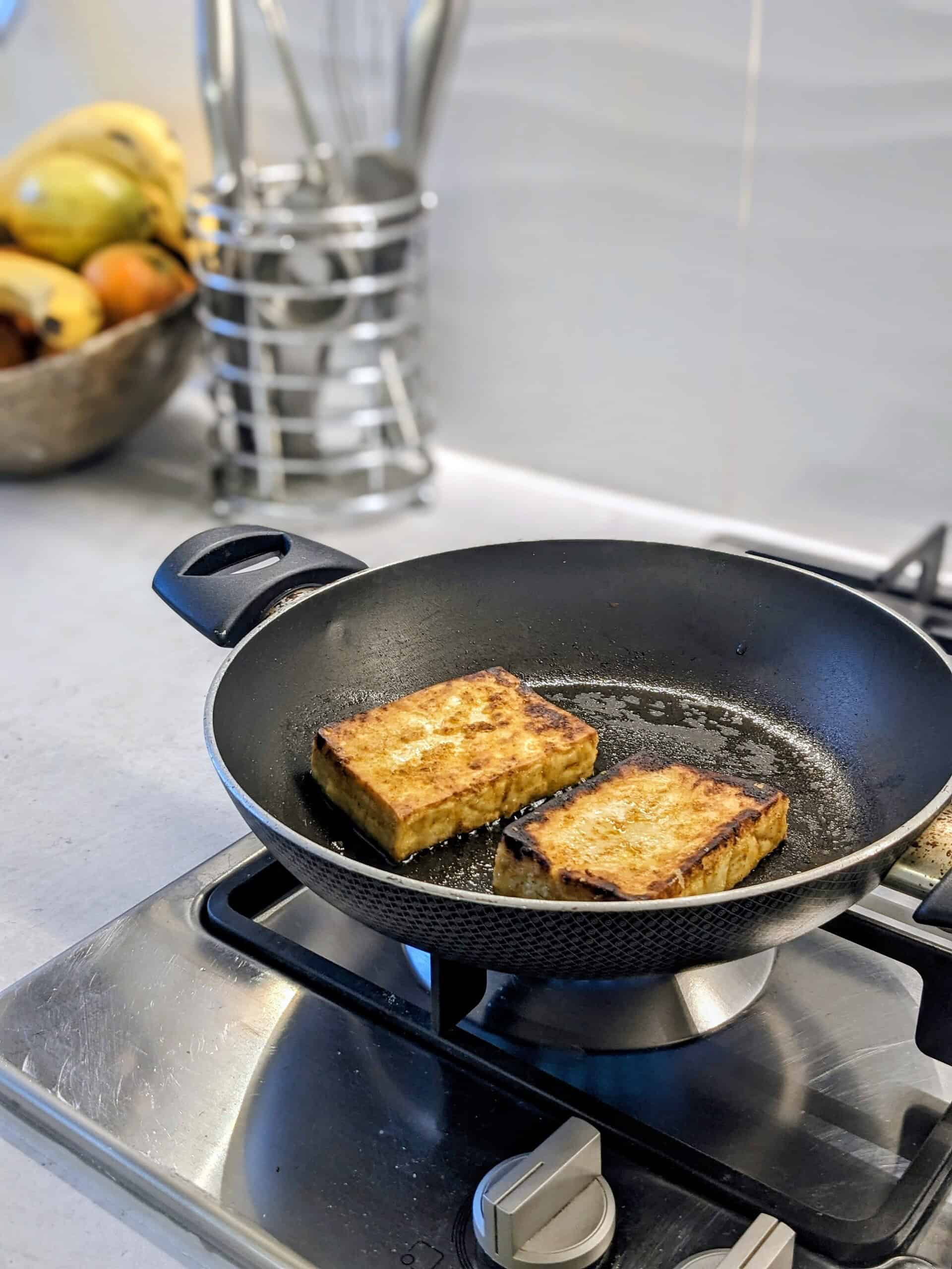A non-stick pan on a gas hob with food frying in it