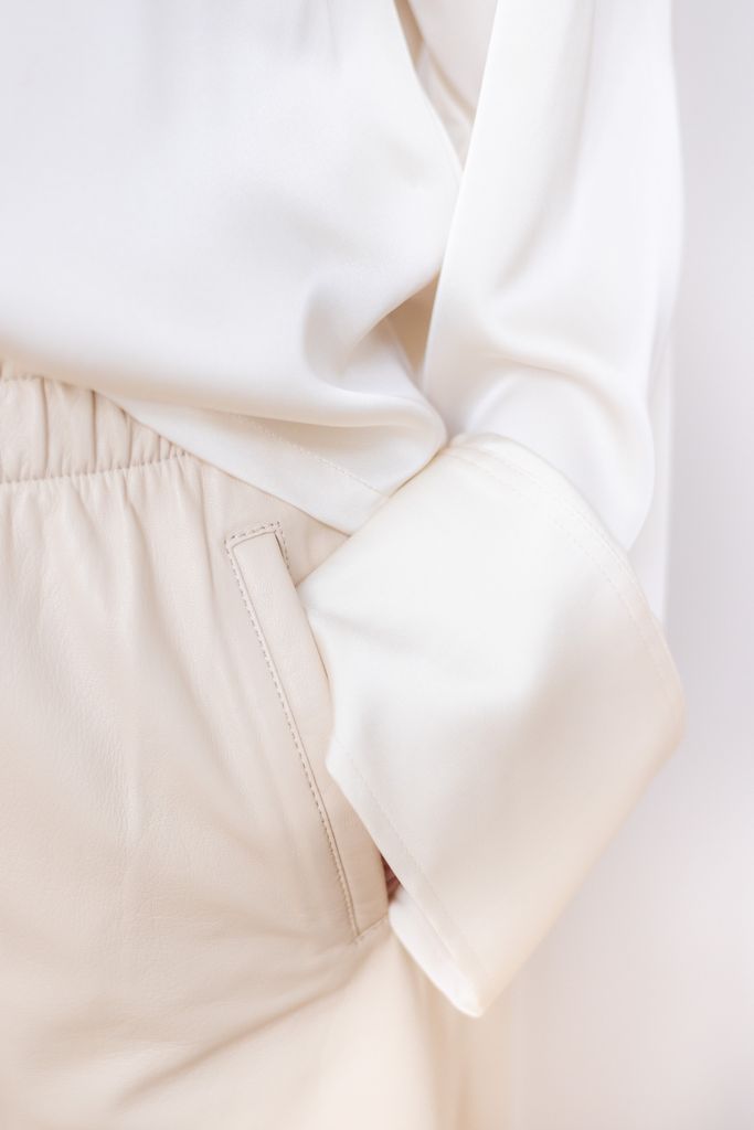 Detailed close-up of a white blouse sleeve and pocket showing soft textures and light fabric.