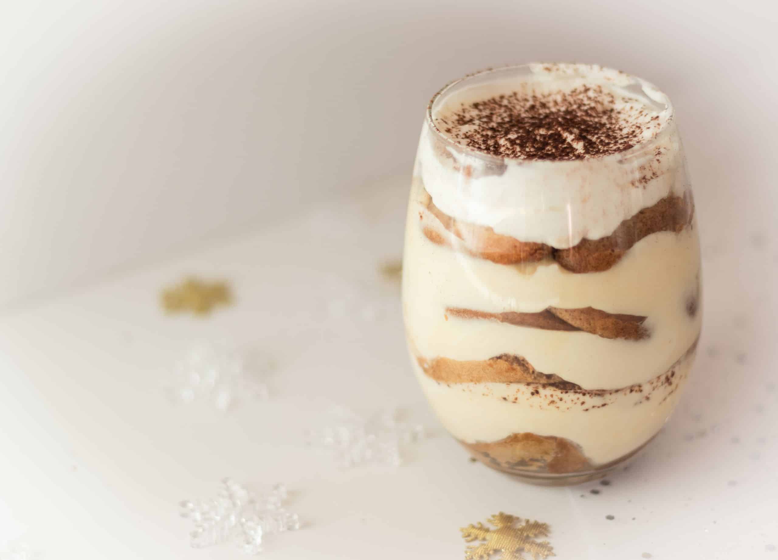 Made-ahead tiramisu served in glass cups, topped with cocoa powder as part of a simple dinner party menu