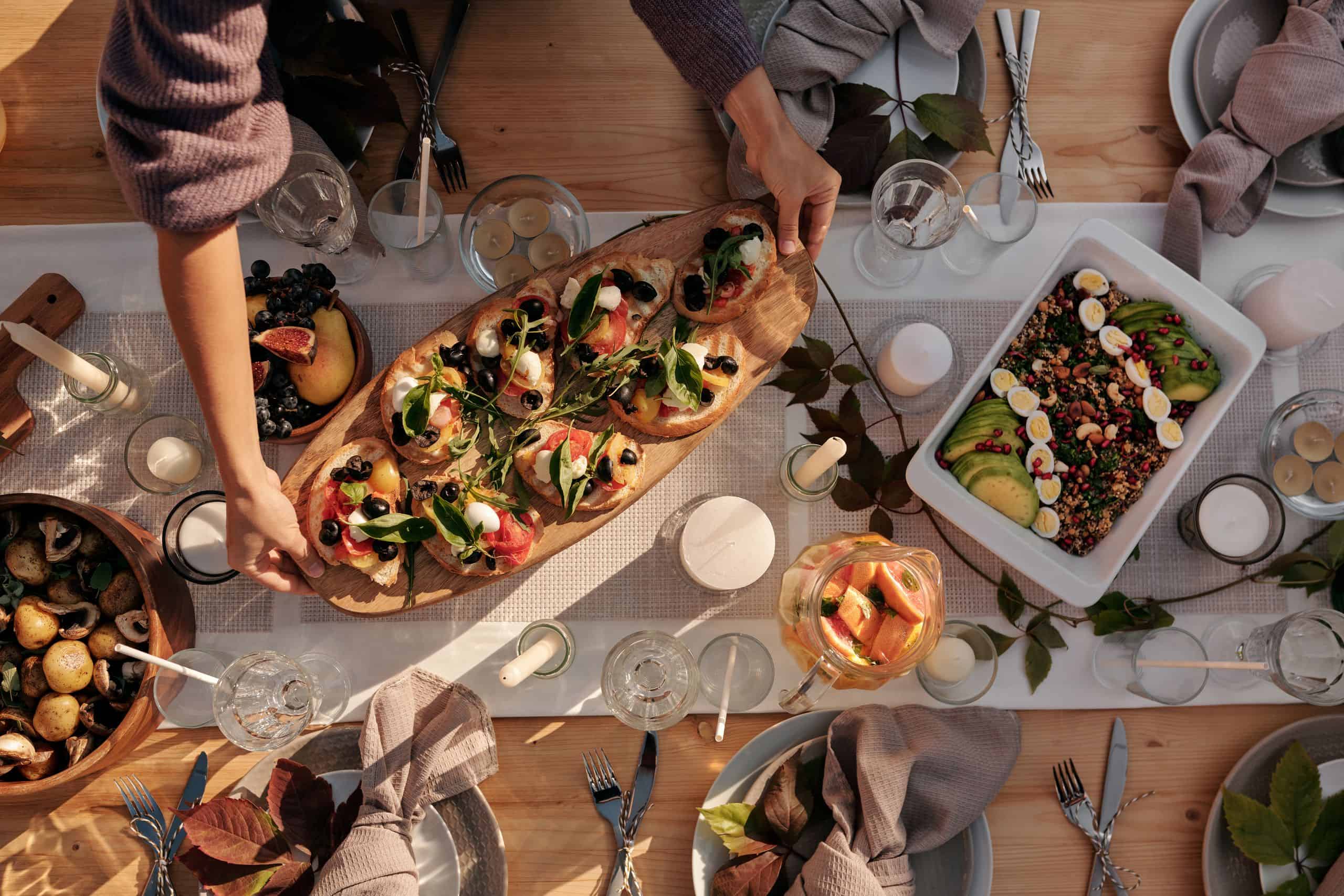 Overhead view of a stylish dinner party setup featuring gourmet dishes with candles and natural decor.