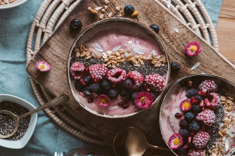 Delicious smoothie bowls topped with fresh berries, chia seeds, and granola on a rustic wooden table.