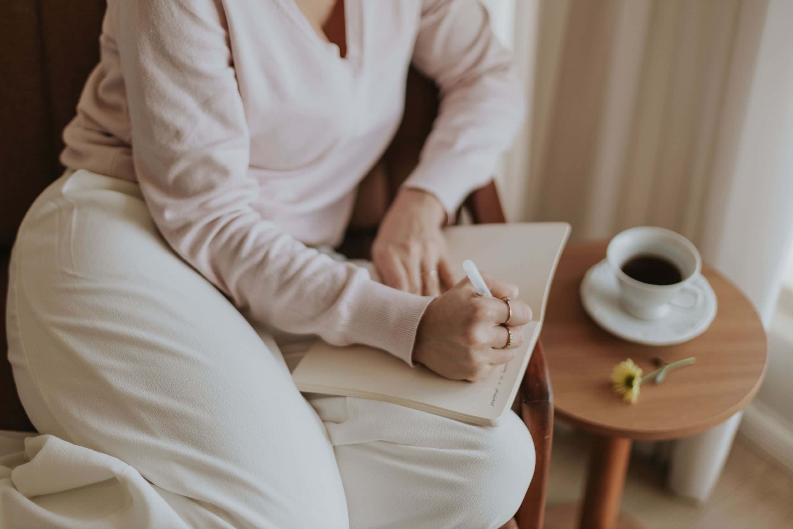 A person with a notebook and coffee cup in in a cozy, bright room illustrating how to do a three day time audit.